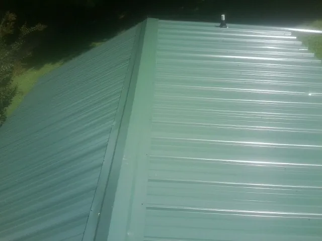 New green metal panels meeting at the ridge of a roof — Flat Roof Repair work by our crew in Sylvia