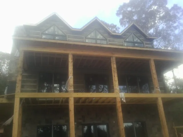Dormers and porch framing on a large log home under construction — Roof Coating work by our crew in Sylvia