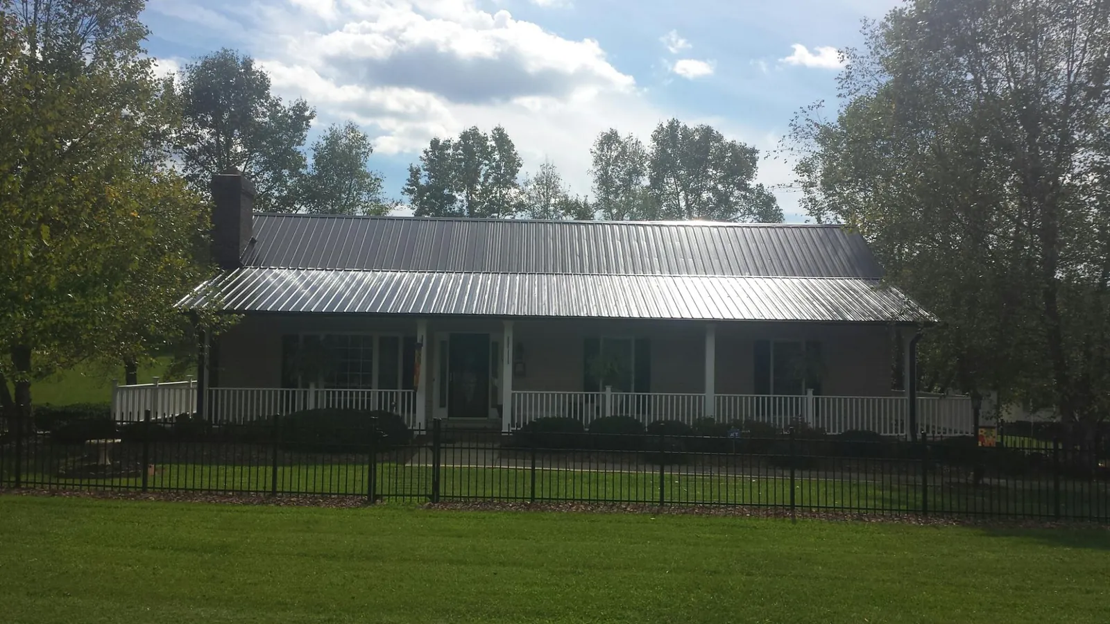 Gray metal roof on a brick ranch with a full width front porch — Gutter Guard Installation work by our crew in Sylvia