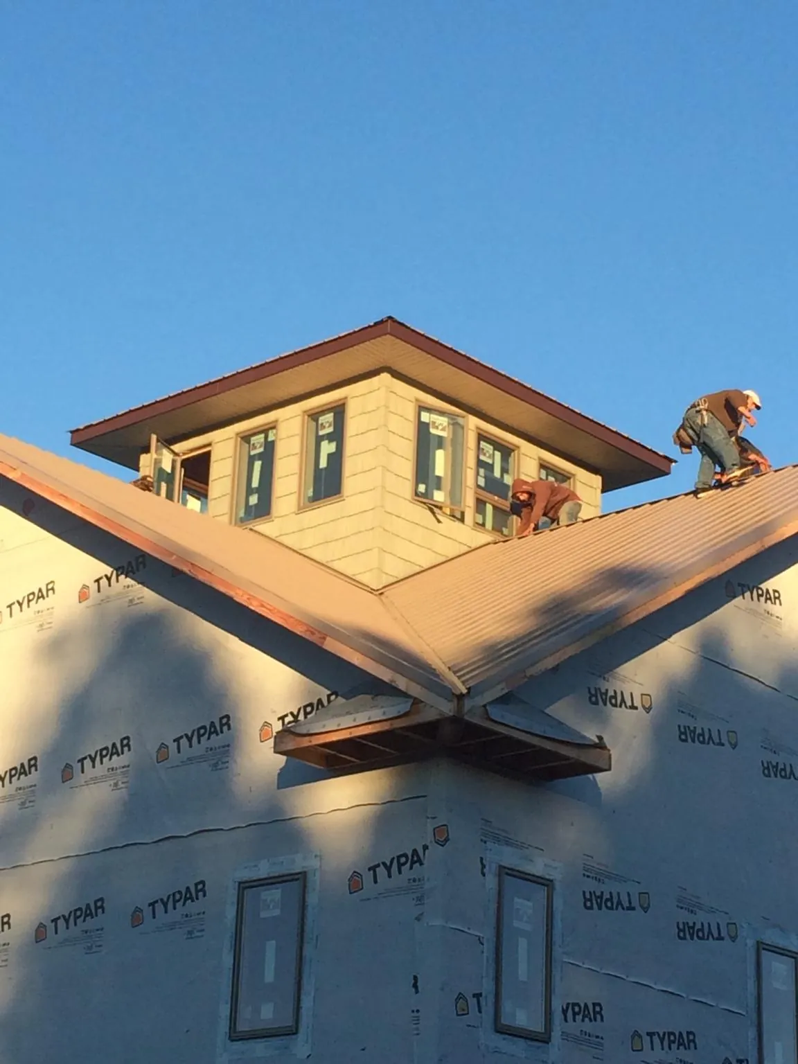 Roofers working around a rooftop cupola on a new metal roof at sunset — Roof Waterproofing in Sylvia by Roofing Brothers